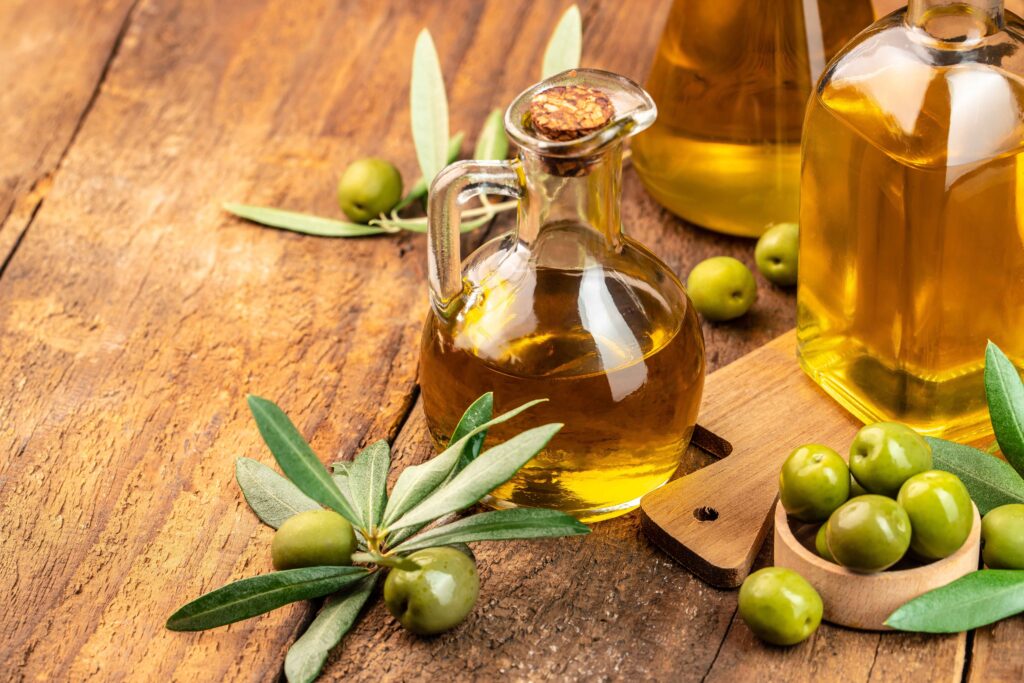 jar of olive oil next to sprigs of green olives