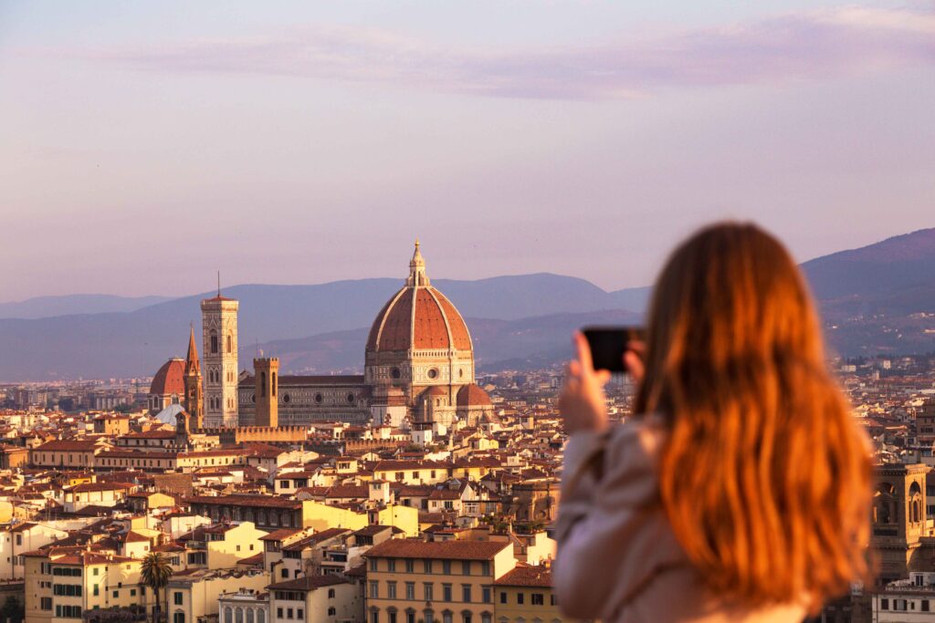 girl taking a photo of florence and the florence duomo with her smartphone